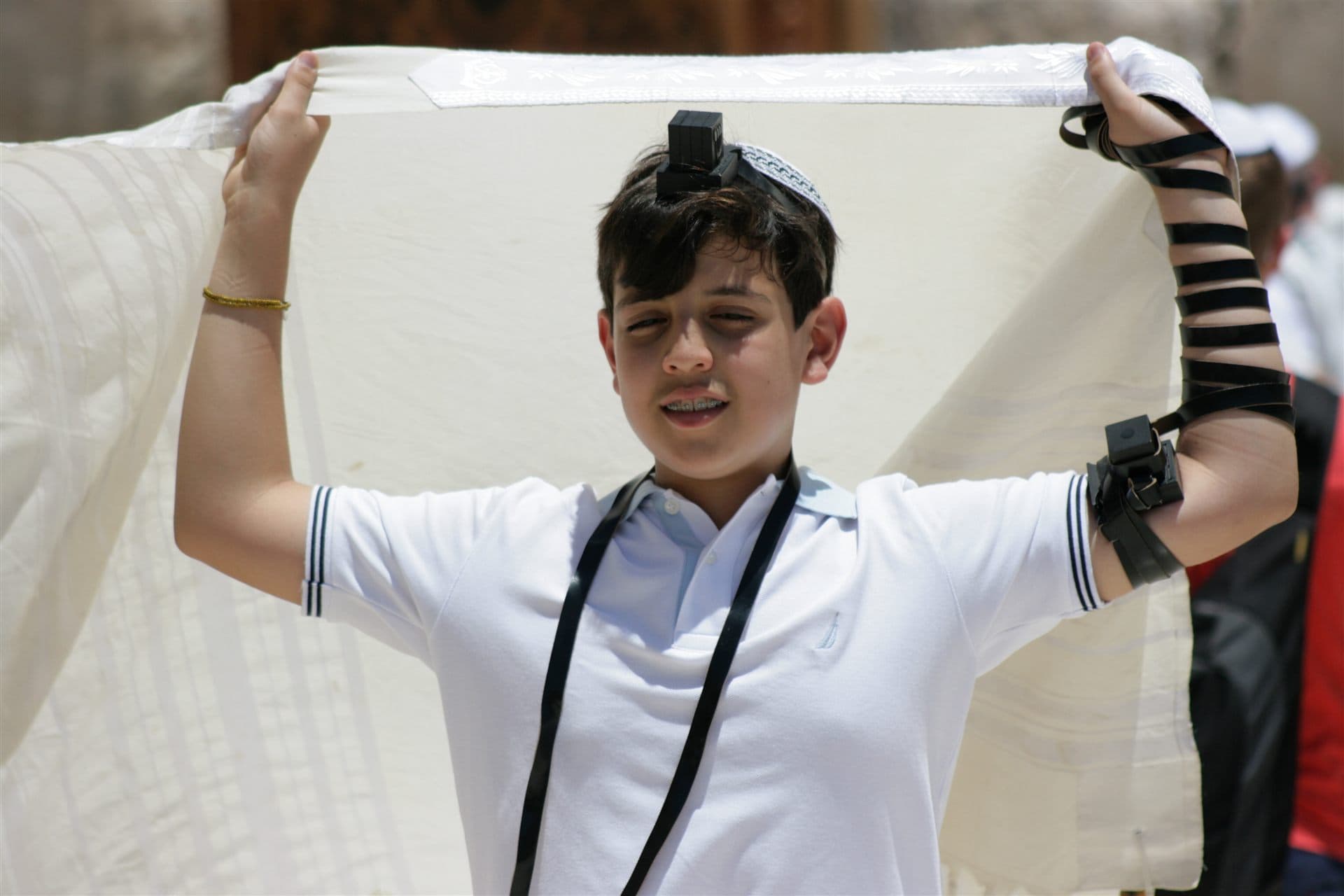 Jewish boy wearing tefillin and holding a tallit during prayer for Maimonides School