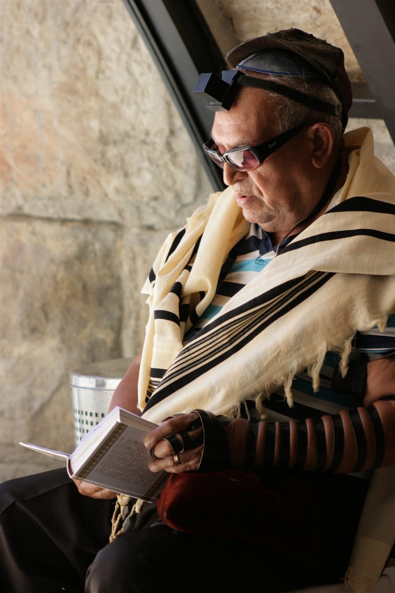 Jewish man wearing tallit and tefillin while reading from a prayer book for Jewish Theological Seminary