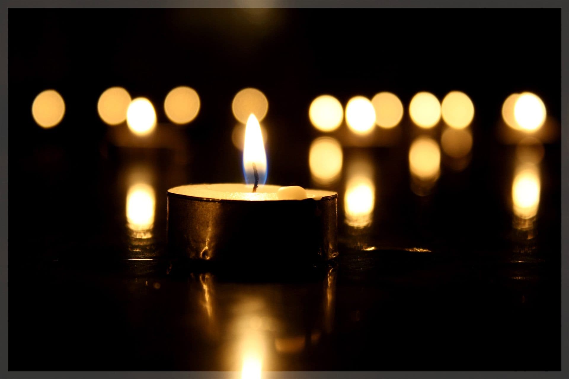 Memorial candle flame glowing in a dark room